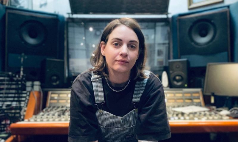 Person sitter framför ett ljudmixbord i en musikstudio.