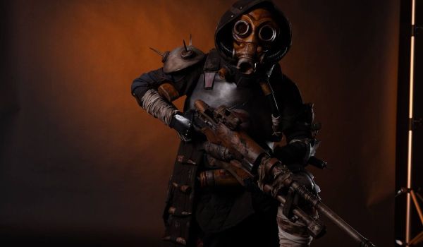 Detaljrik cosplay-dräkt i postapokalyptisk stil med gasmask och ett stort, patinerat gevär i mjuk studiobelysning.