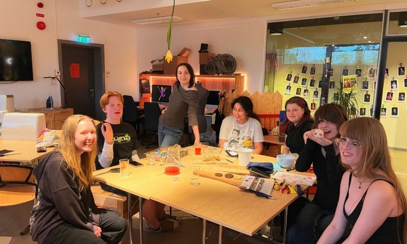 En bild på en grupp unga som sitter samlade runt ett bord och skapar.