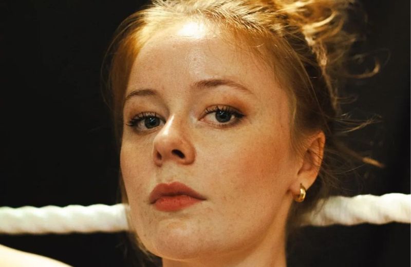 Porträtt i närbild av Maja Fock med uppsatt hår och ett vitt rep i bakgrunden.