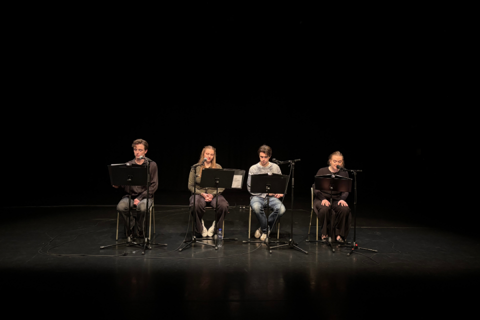 Sceniskt collage där fyra ungdomar gör en läsning vid mikrofoner i ett djupt scenmörker.