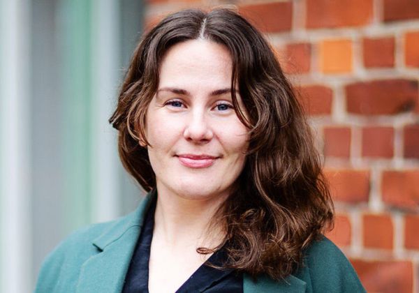Porträtt av Malin Hadarsson Bodin, ansvarig för UKM. Hon har axellångt brunt hår och bär en mörkgrön kavaj.