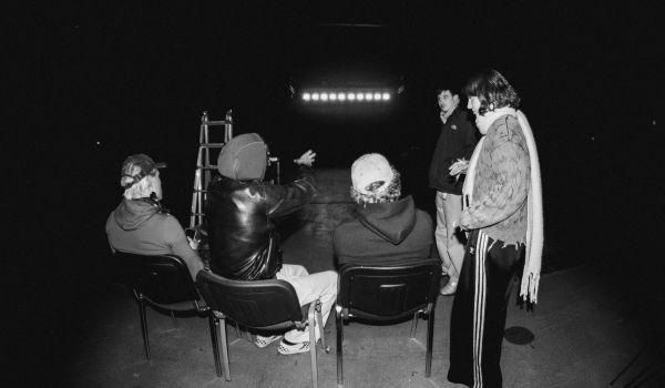 Fem personer samlade i en mörk lokal framför en upplyst scenkant.