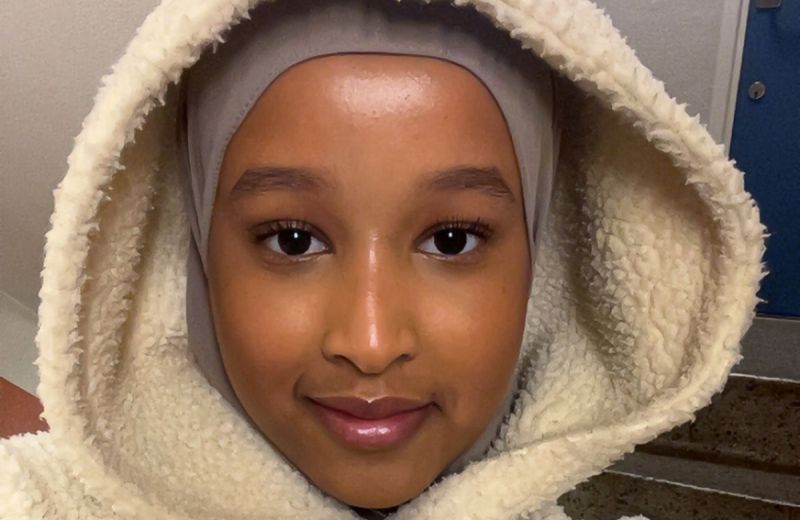 Närbild på poeten Fardowsa Adam som ler mot kameran i en luddig huvtröja.