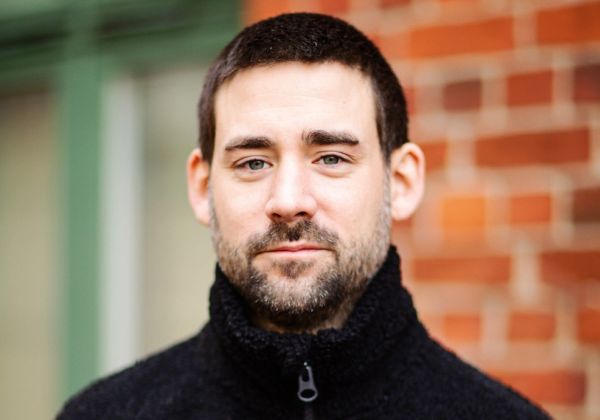 Porträtt av Tobias Söderman, ansvarig för kommunikation och IT. Han har kort mörkt hår och skäggstubb och bär en svart fleecejacka.