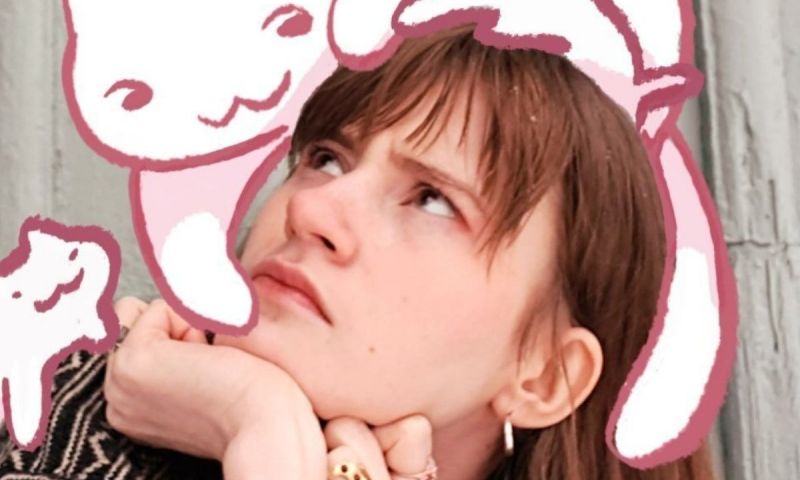 Porträtt på en person med blicken vänd uppåt, omgiven av lekfulla, rosa illustrationer av katter.