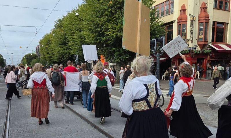 Människor i folkdräkter demonstrerar på en öppen gata med skyltar i händerna.