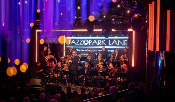 Bild på ett band på scen, med texten "Jazzopark Lane" som bakgrund