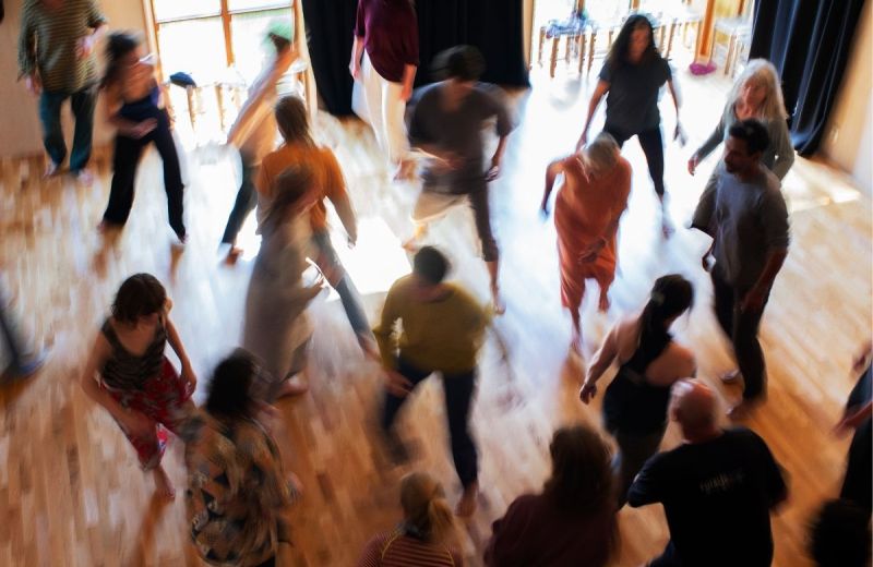 En grupp människor rör sig tillsammans i en ljus sal, fångade i en suddig rörelseoskärpa.