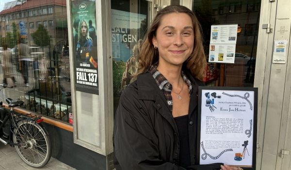 Vinnaren av Kultur Ungdoms filmpris poserar stolt med sitt inramade diplom utanför Bio Capitol.