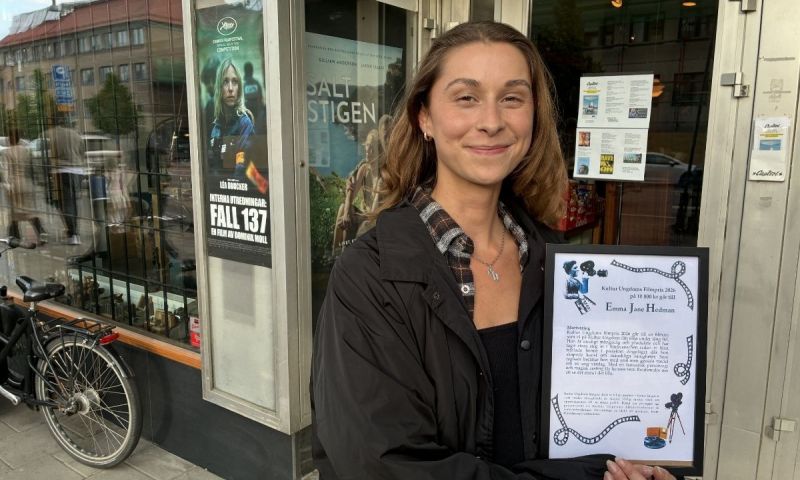 Vinnaren av Kultur Ungdoms filmpris poserar stolt med sitt inramade diplom utanför Bio Capitol.