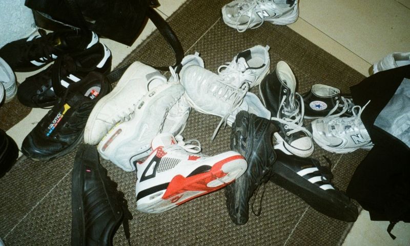 En salig blandning av olika sneakers ligger slängda på en dörrmatta.