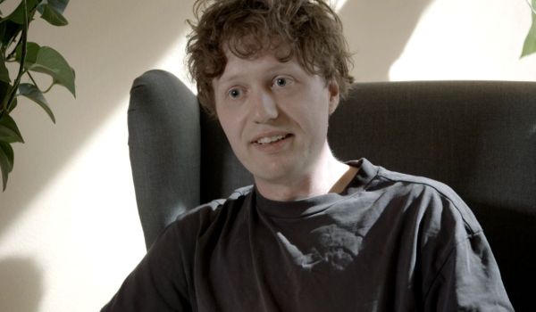 Truls, en man med lockigt hår sitter i en fåtölj och pratar.