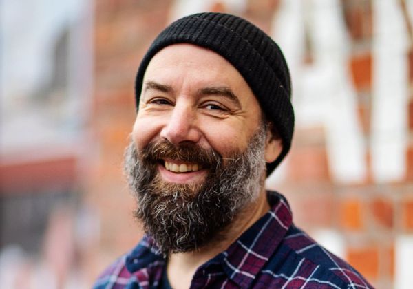 Porträtt av Joen Windahl, konsulent för film och K-pengar. Han har ett stort grått skägg, bär en svart sotarmössa och en rutig flanellskjorta.