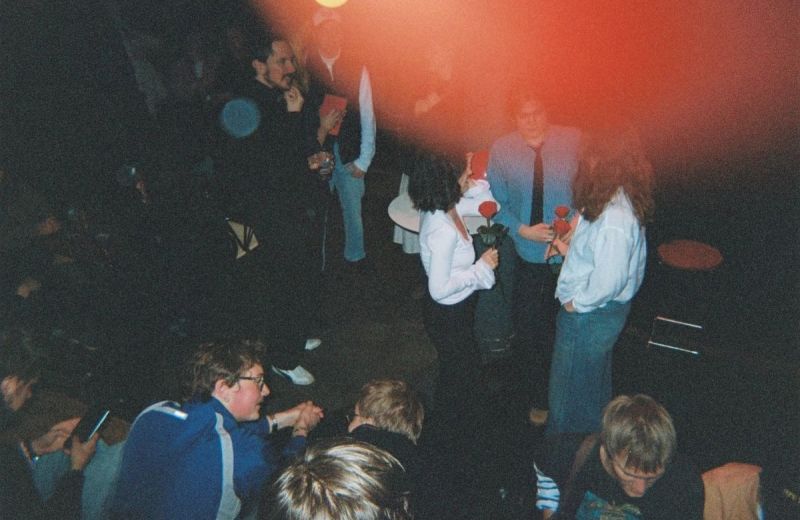Ungdomar pratar och umgås i en röd-belyst lokal.