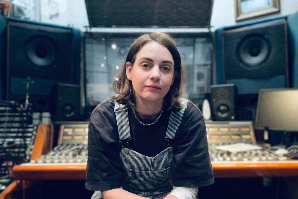 Person sitter framför ett ljudmixbord i en musikstudio.
