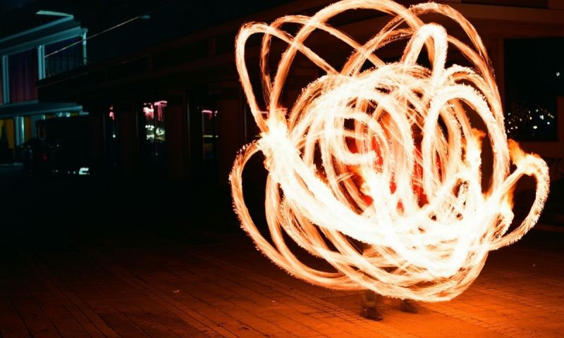 Virvlande eldspår bildar ljuscirklar runt en person på en mörk gård