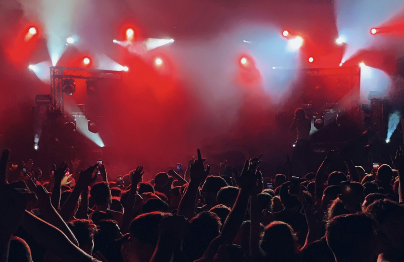 Konsertpublik sträcker händerna mot scenen under starka röda och vita scenljus