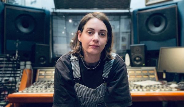 Person sitter framför ett ljudmixbord i en musikstudio.