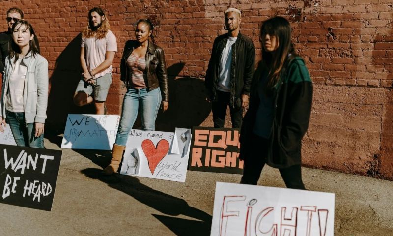 Samling av ungdomar med skyltar för rättvisa och fred, uttrycker engagemang och allvar.