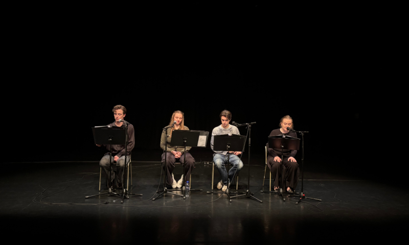 Sceniskt collage där fyra ungdomar gör en läsning vid mikrofoner i ett djupt scenmörker.