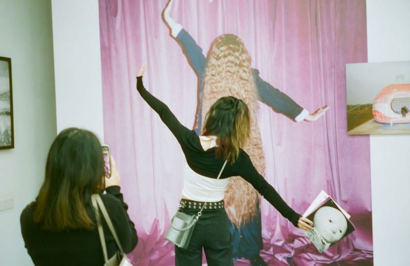 Två personer utforskar en konstinstallation med rosa draperier och skulpturer på en UKM-festival.